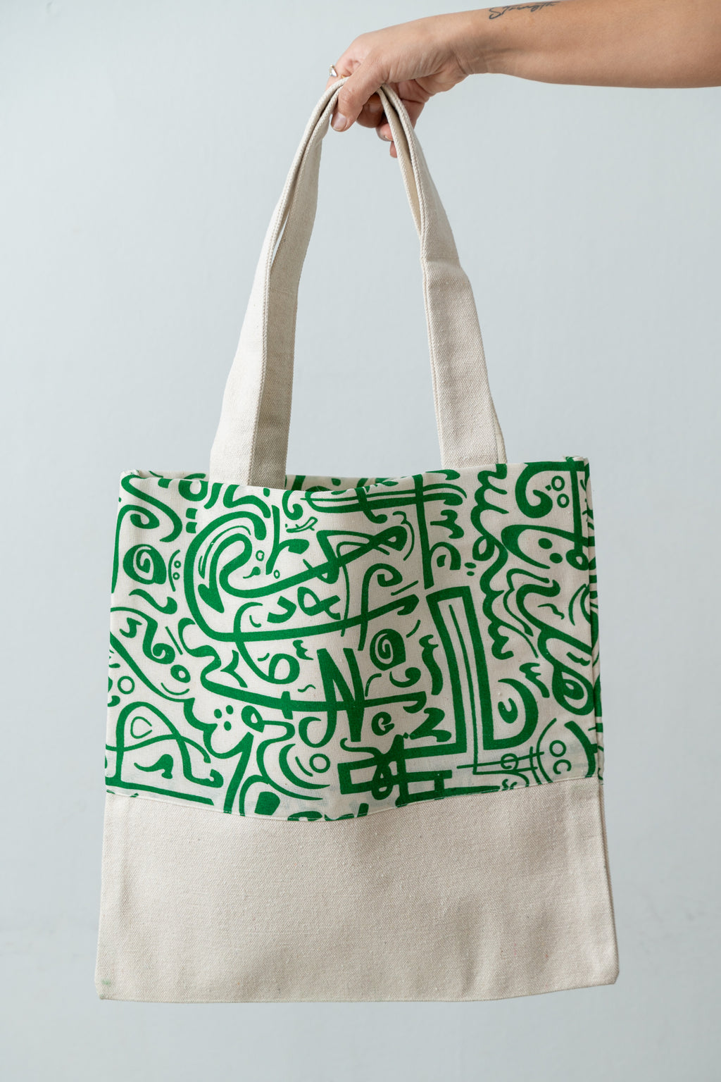 Green Calligraphy Tote – natural DAKK tote with a green Arabic calligraphy-inspired print, by Noha Fathy