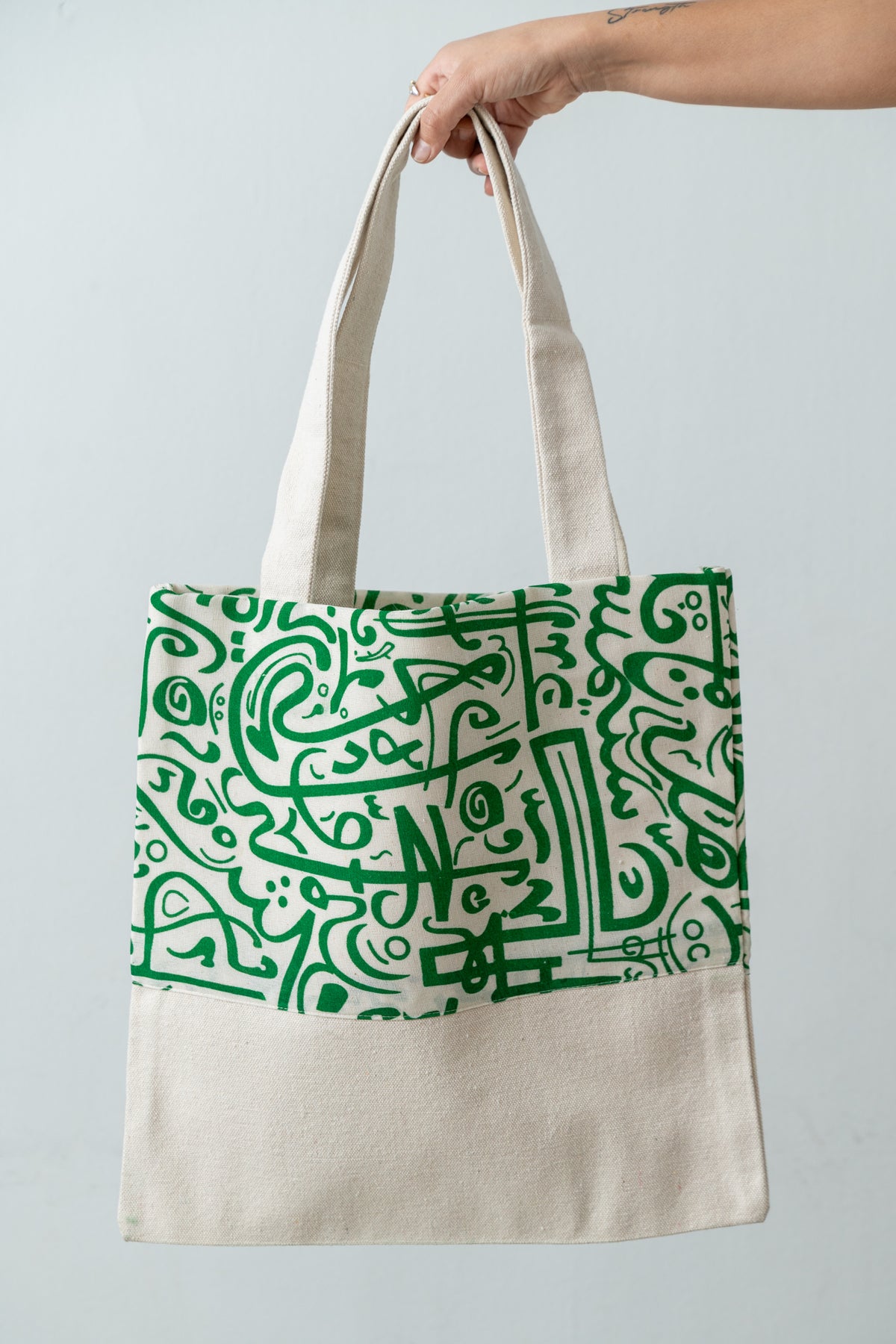 Green Calligraphy Tote – natural DAKK tote with a green Arabic calligraphy-inspired print, by Noha Fathy