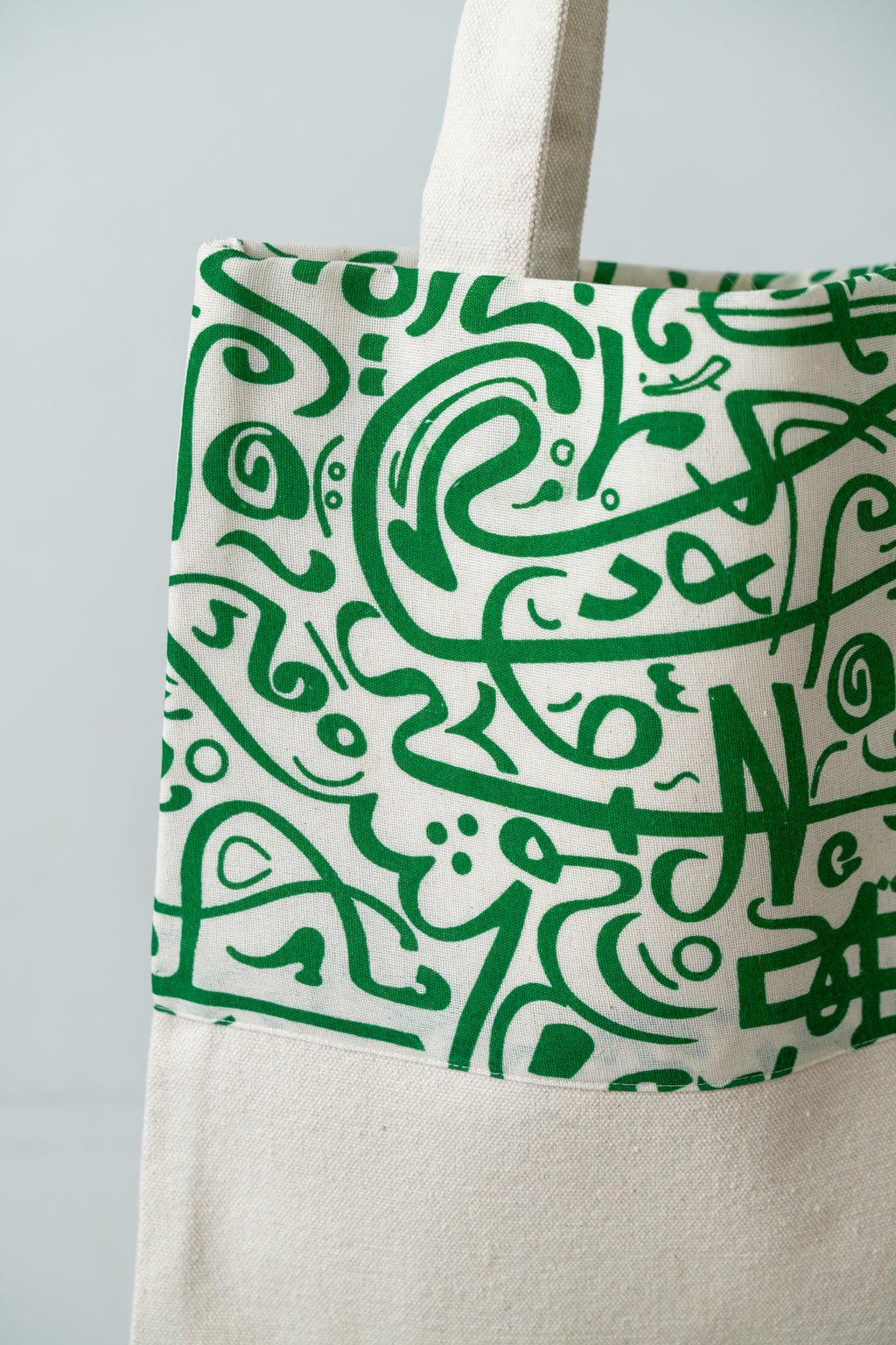 Green Calligraphy Tote – close-up of the green calligraphy print on natural fabric, by Noha Fathy