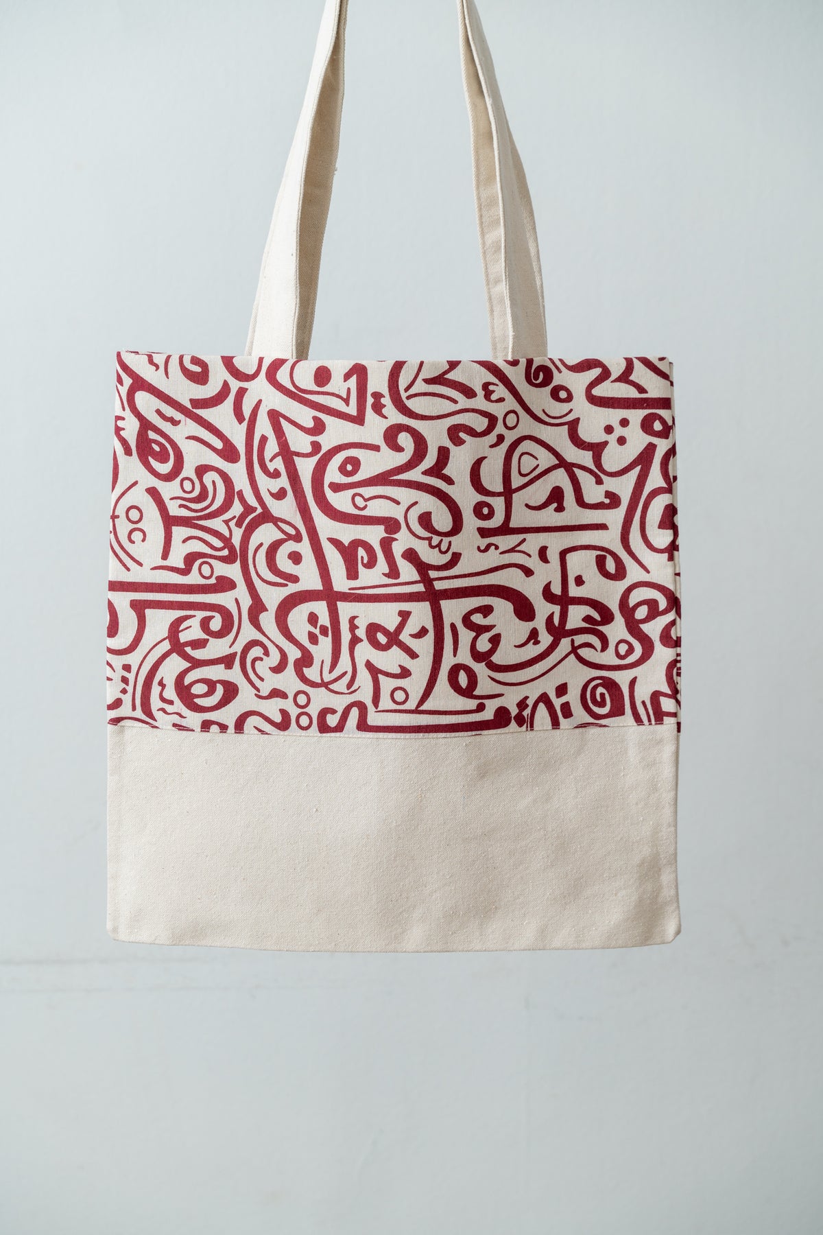 Red Calligraphy Tote – natural DAKK tote with a red Arabic calligraphy-inspired print, by Noha Fathy