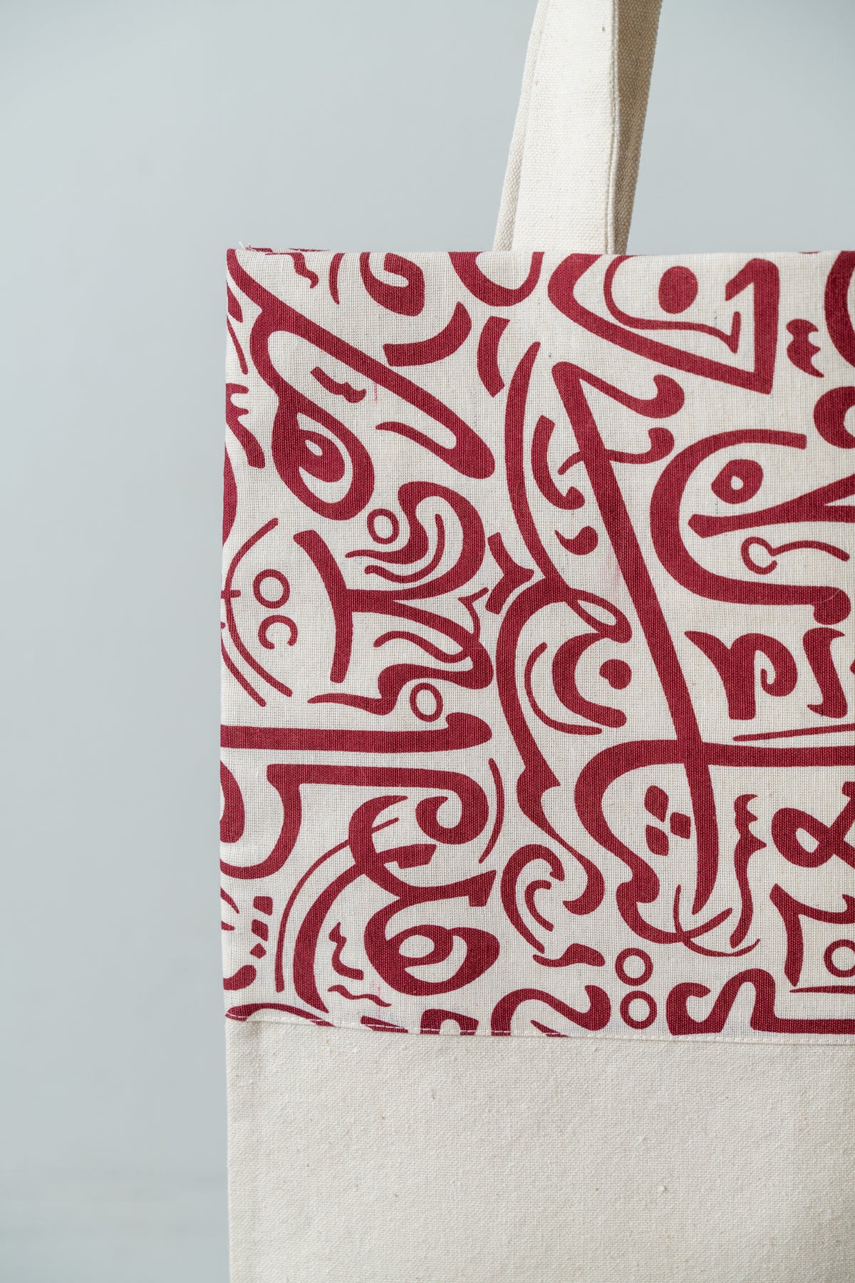 Red Calligraphy Tote – close-up of the red calligraphy print on natural fabric, by Noha Fathy